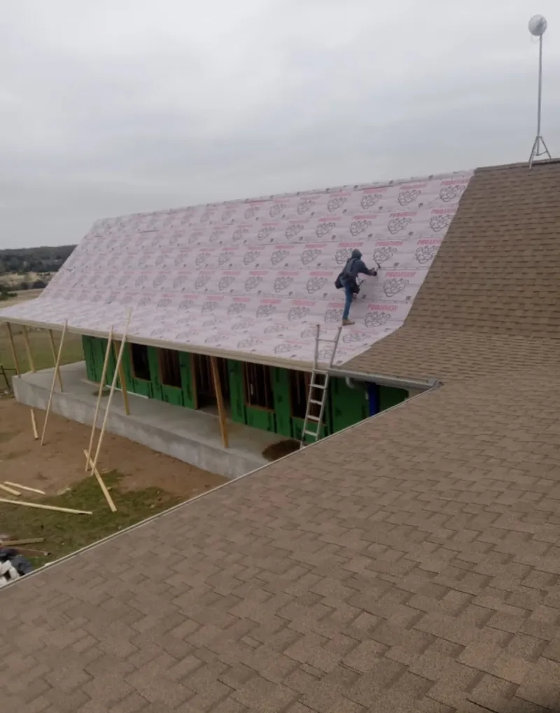 Worker preparing underlayment for a metal roof installation in Washington